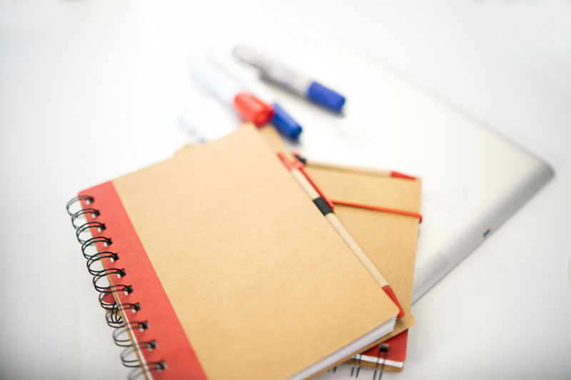 Two brown coloured spiral notebooks on top of each other, on a white desk