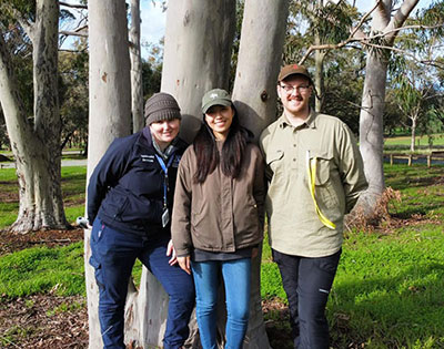 Two University of Melbourne interns and one staff member standing in front of a eucalyptus tree at Sheparton campus 