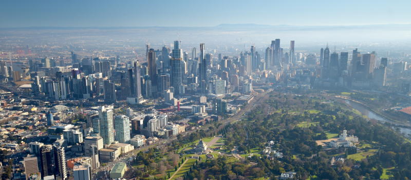 Wide photo from the air of Melbourne's city skyline, including the shrine of remembrance in the front and the CBD skyscrapers behind.